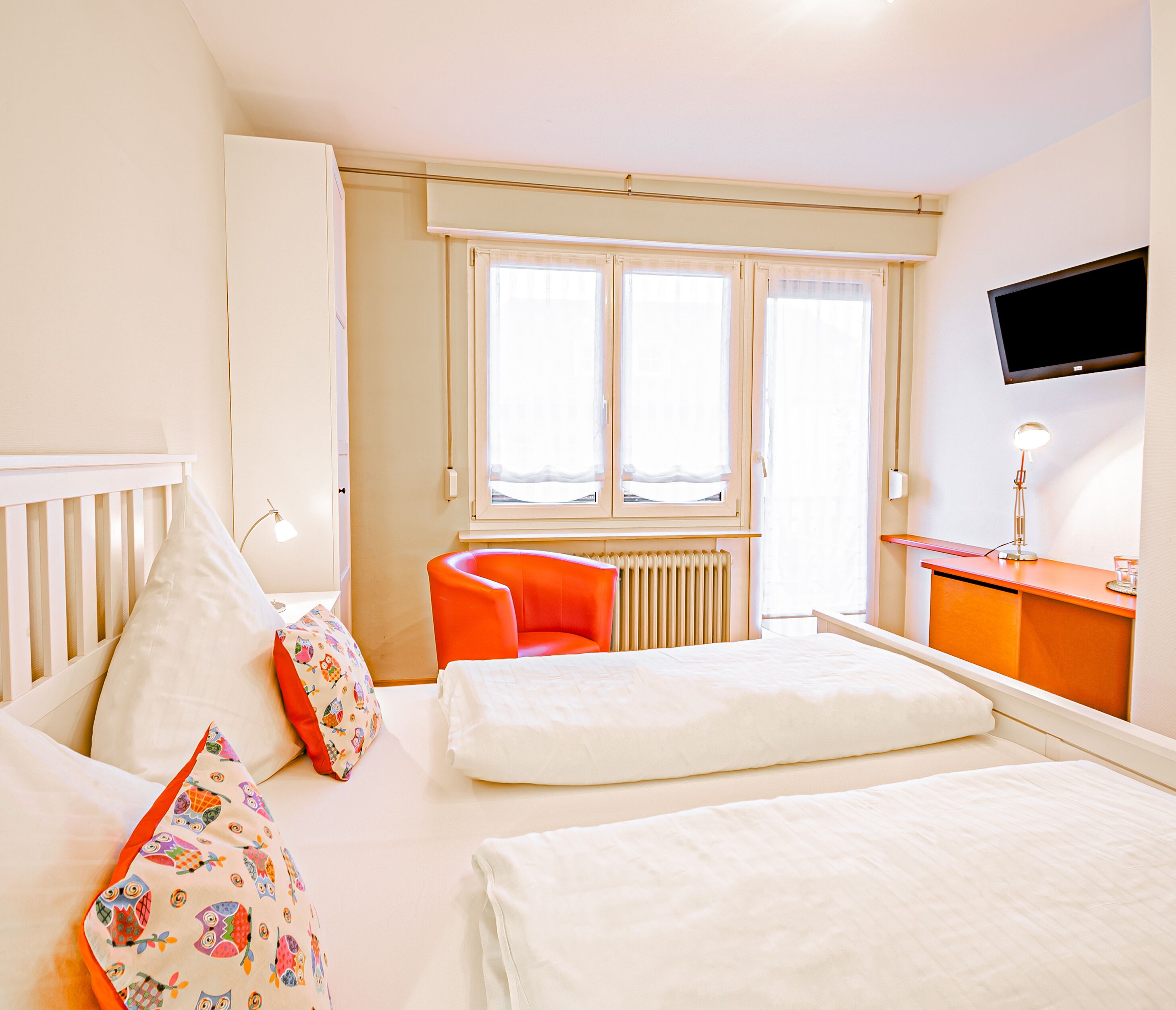 Ein Hotelzimmer mit Bett, Schreibtisch, Sessel und Fernseher.