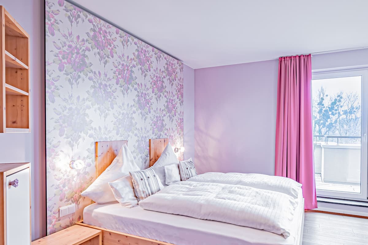 Une chambre à coucher avec un grand lit, une tête de lit en bois, une table de chevet, une armoire et une fenêtre avec des rideaux.