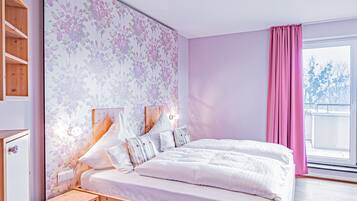 A bedroom with a large bed, wooden headboard, a nightstand, a wardrobe, and a window with curtains.