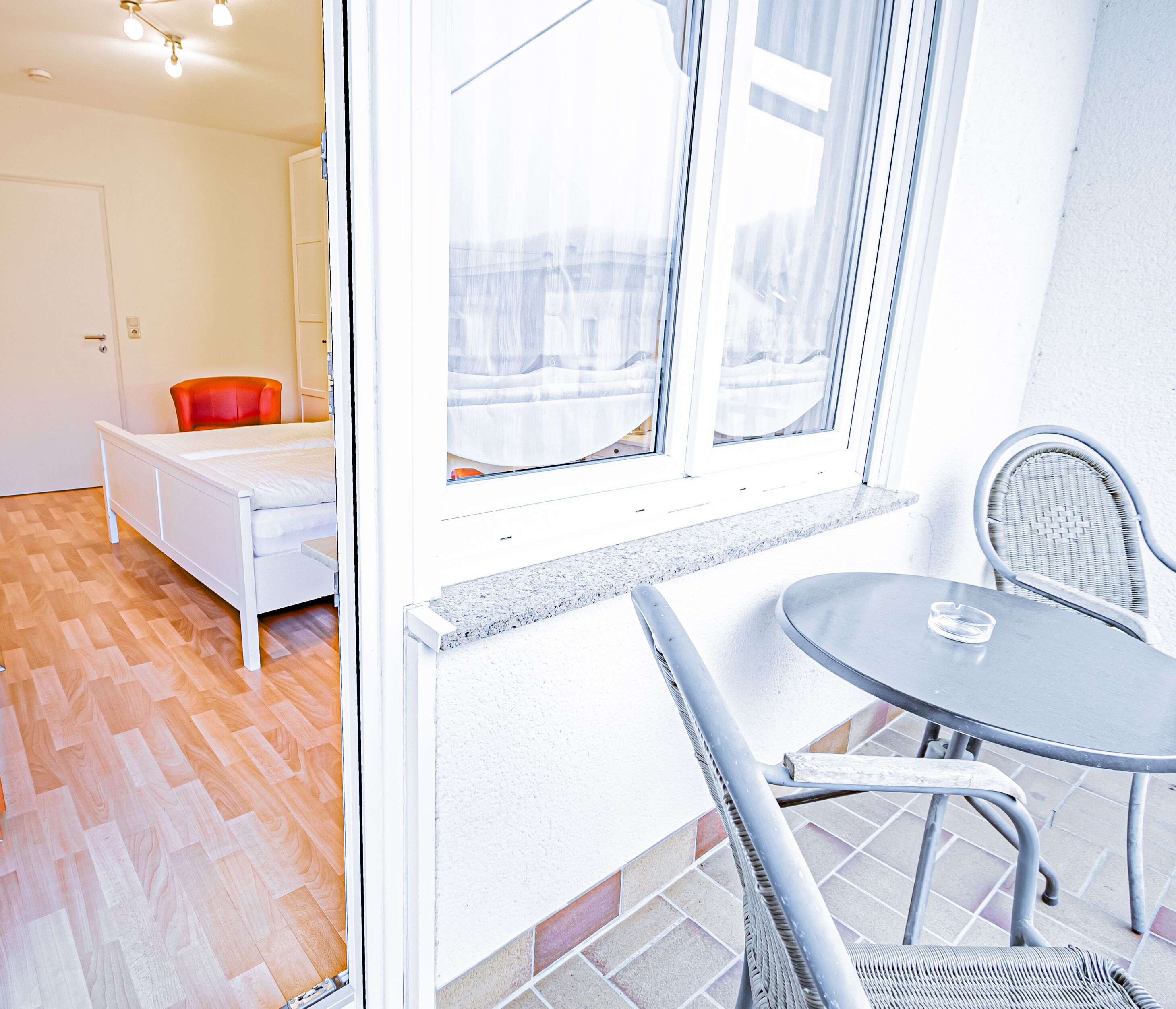 A room with a bed, a chair, and a table by a window.