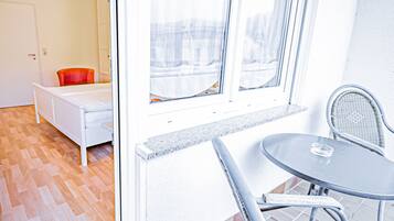 Una habitación con una cama, una silla y una mesa junto a una ventana.