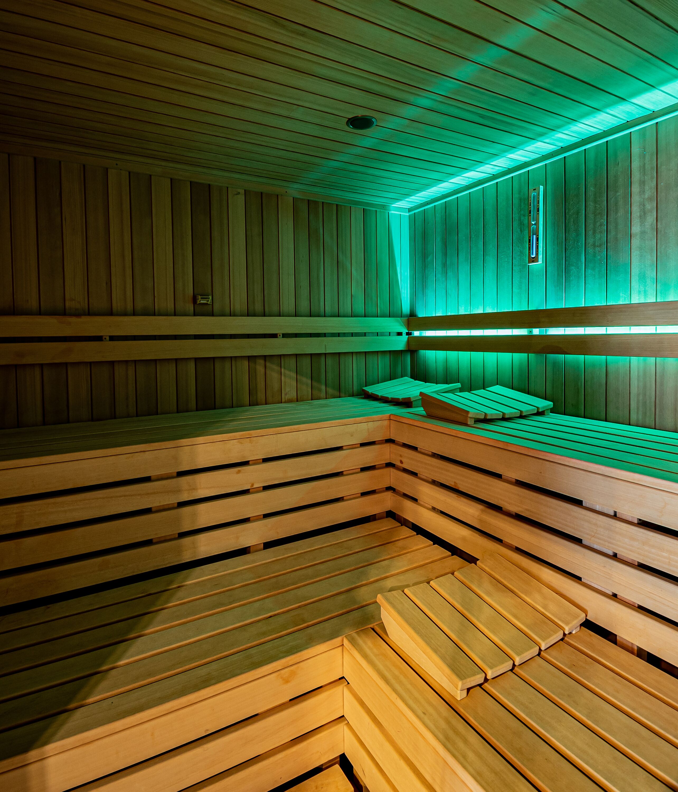 Eine Sauna mit Holzbänken und grüner Beleuchtung.