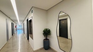A corridor with doors, a potted plant, and a large mirror on the wall. - Villalba Hotel Uberlandia (Uberlandia)