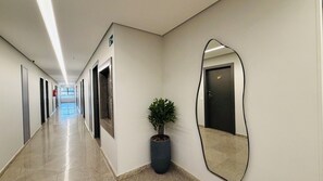 Ein Korridor mit Türen, einem Blumentopf und einem großen Spiegel an der Wand.
