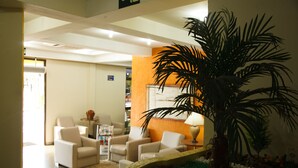 A modern lobby with a reception desk, seating area, and a decorative plant arrangement.