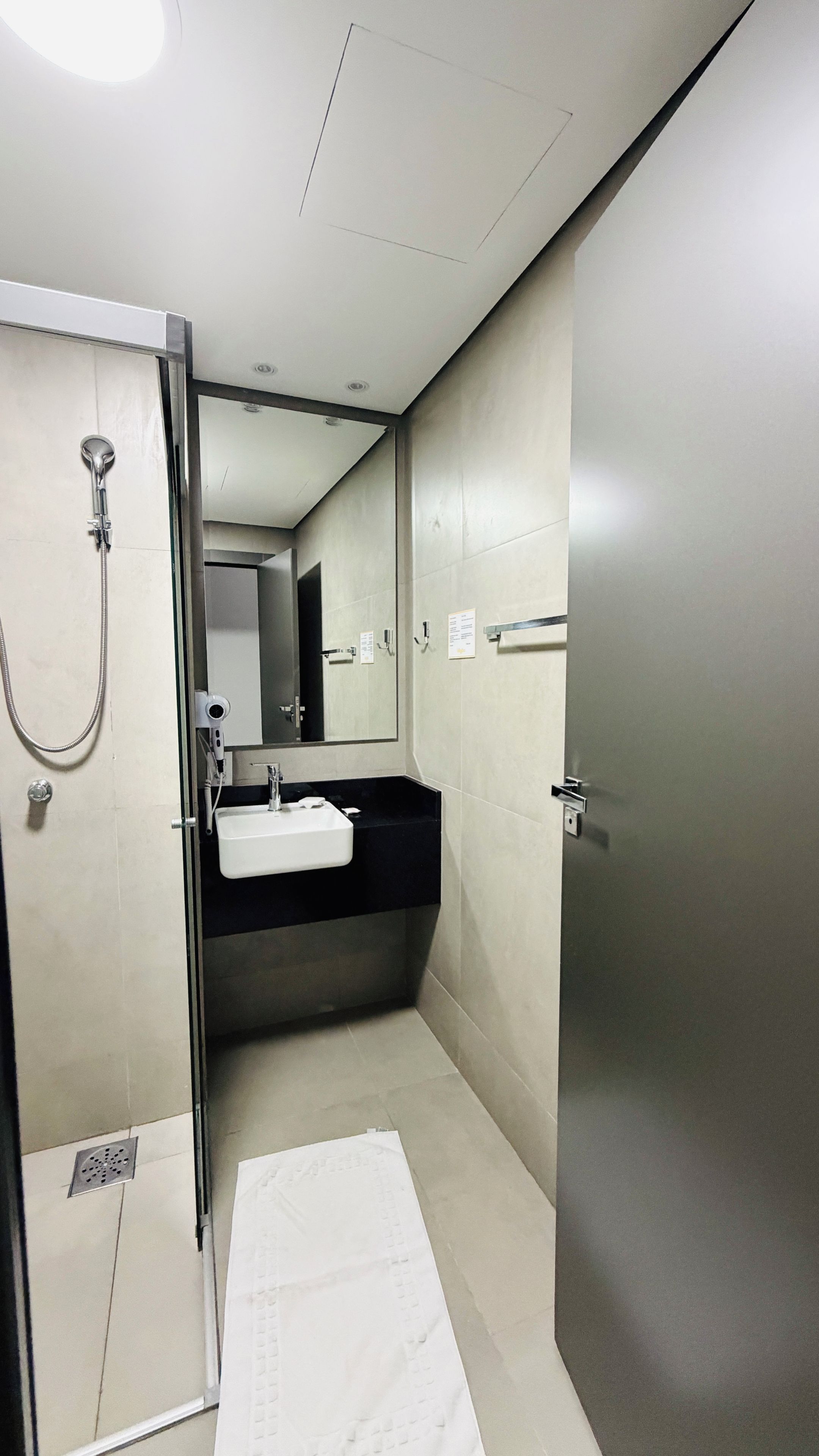 Un baño moderno con ducha envuelta en vidrio, un lavabo y un espejo.