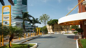 A hotel entrance with a curved pathway, palm trees, and a large building with a sign.