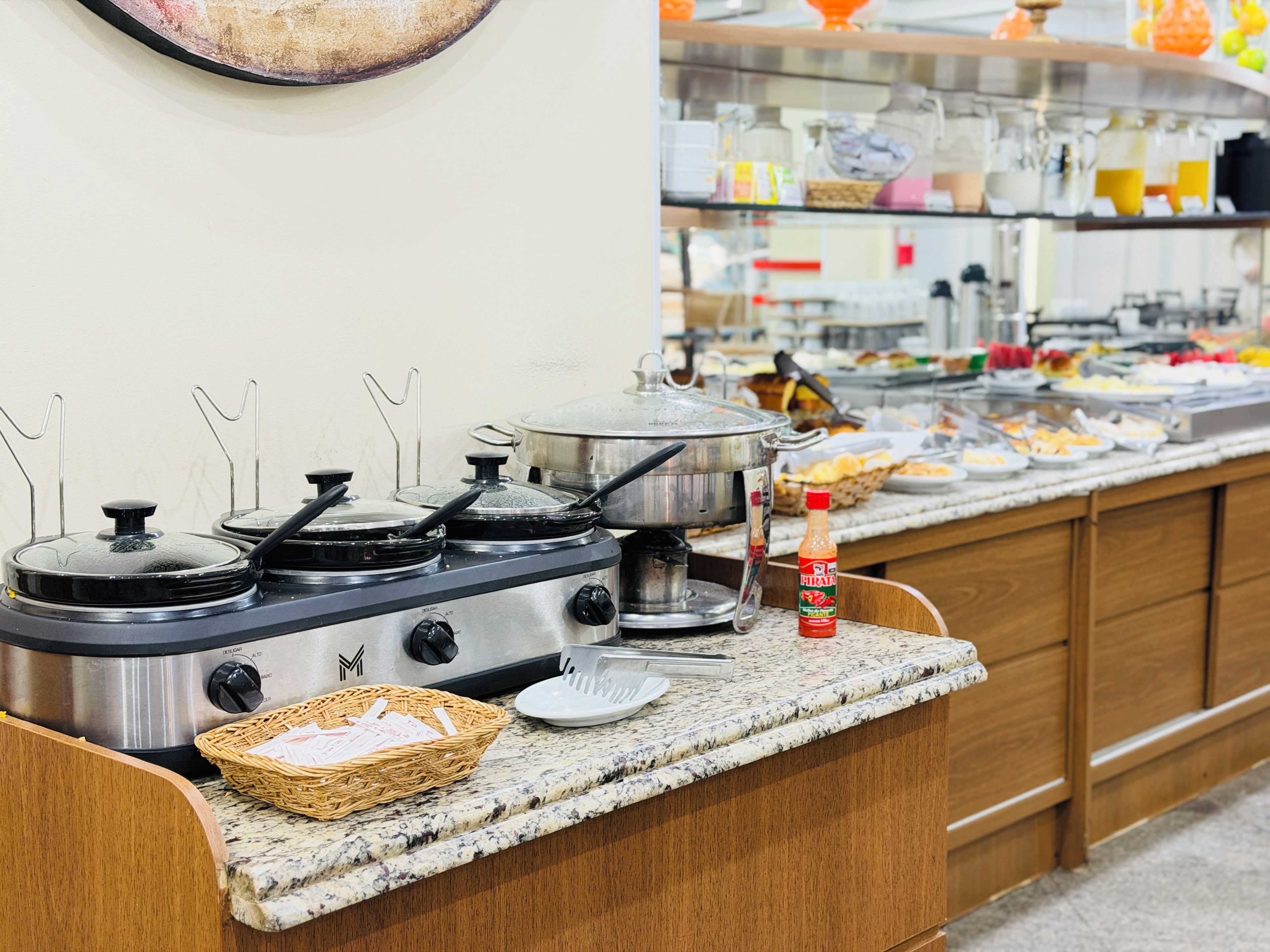 Un coin cuisine avec une cuisinière, des casseroles, un panier et une bouteille posés sur le comptoir.