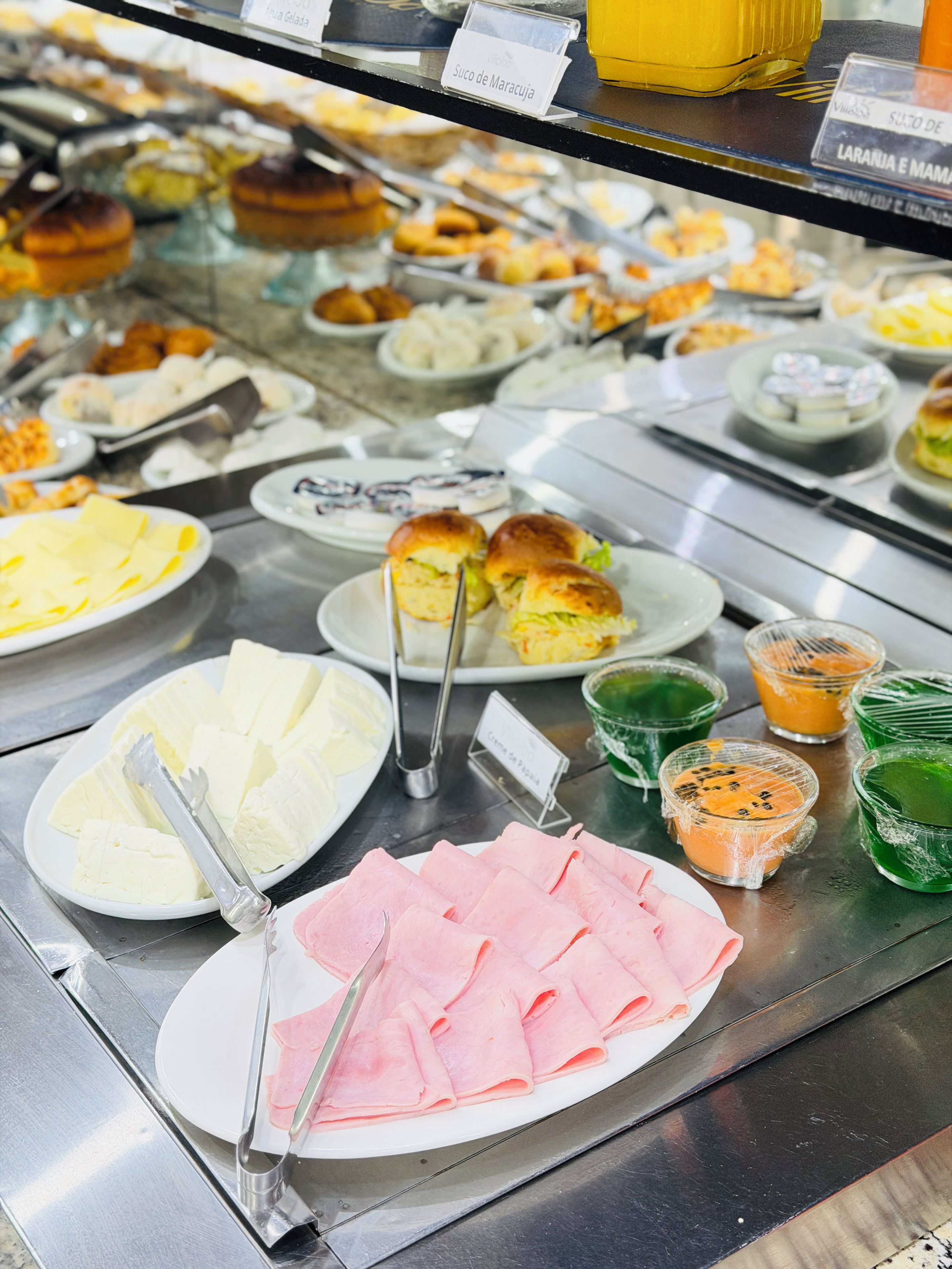 A buffet with various food items including sliced cheese, ham, and a variety of desserts.