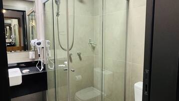 A modern bathroom with a glass-enclosed shower, a toilet, and a sink with a mirror.