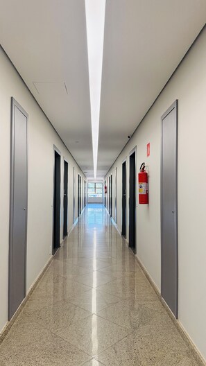 Ein langer, gerader Flur mit Türen an beiden Seiten, einem an der Wand befestigten Feuerlöscher und einem Fenster am Ende.