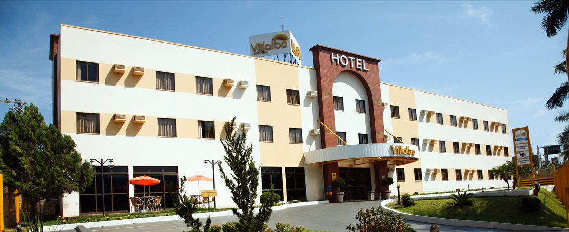 Een hotel met een centrale ingang, meerdere verdiepingen en een bord met de naam.