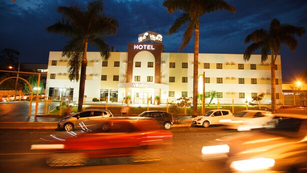 A hotel with a prominent "HOTEL" sign, multiple floors, and palm trees in the foreground.