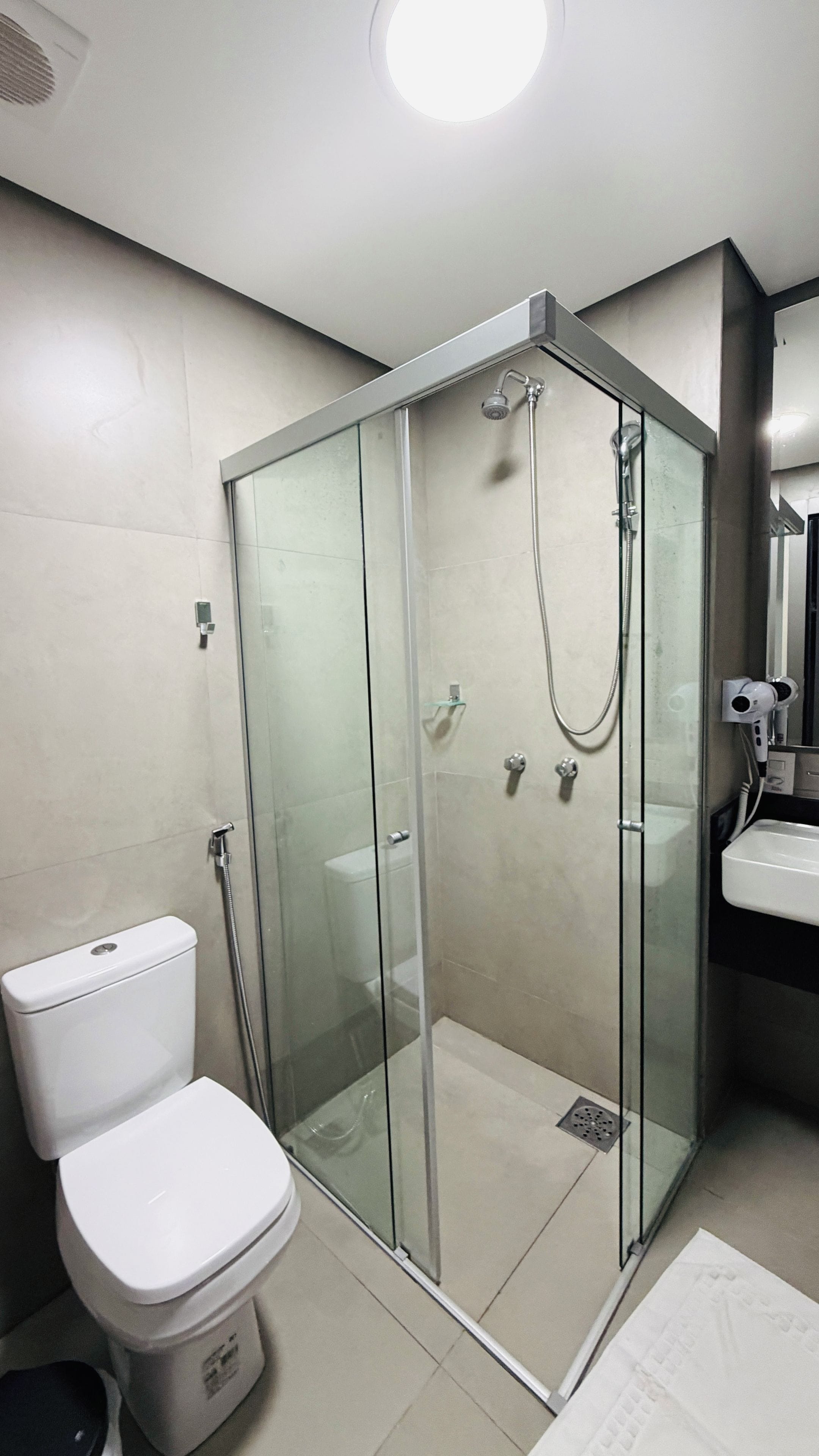 Un baño moderno con ducha envuelta en vidrio, inodoro y lavamanos.