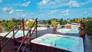A rooftop with hot tubs and wooden stairs. - Pousada Marie Claire Flats (Ipojuca)