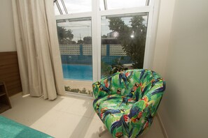 Relax by the pool from the comfort of your room, featuring an access door and a stylish armchair.