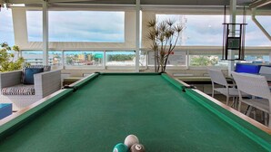 A pool table with a green felt surface, surrounded by wicker chairs and a sofa. - Pousada Marie Claire Flats (Ipojuca)