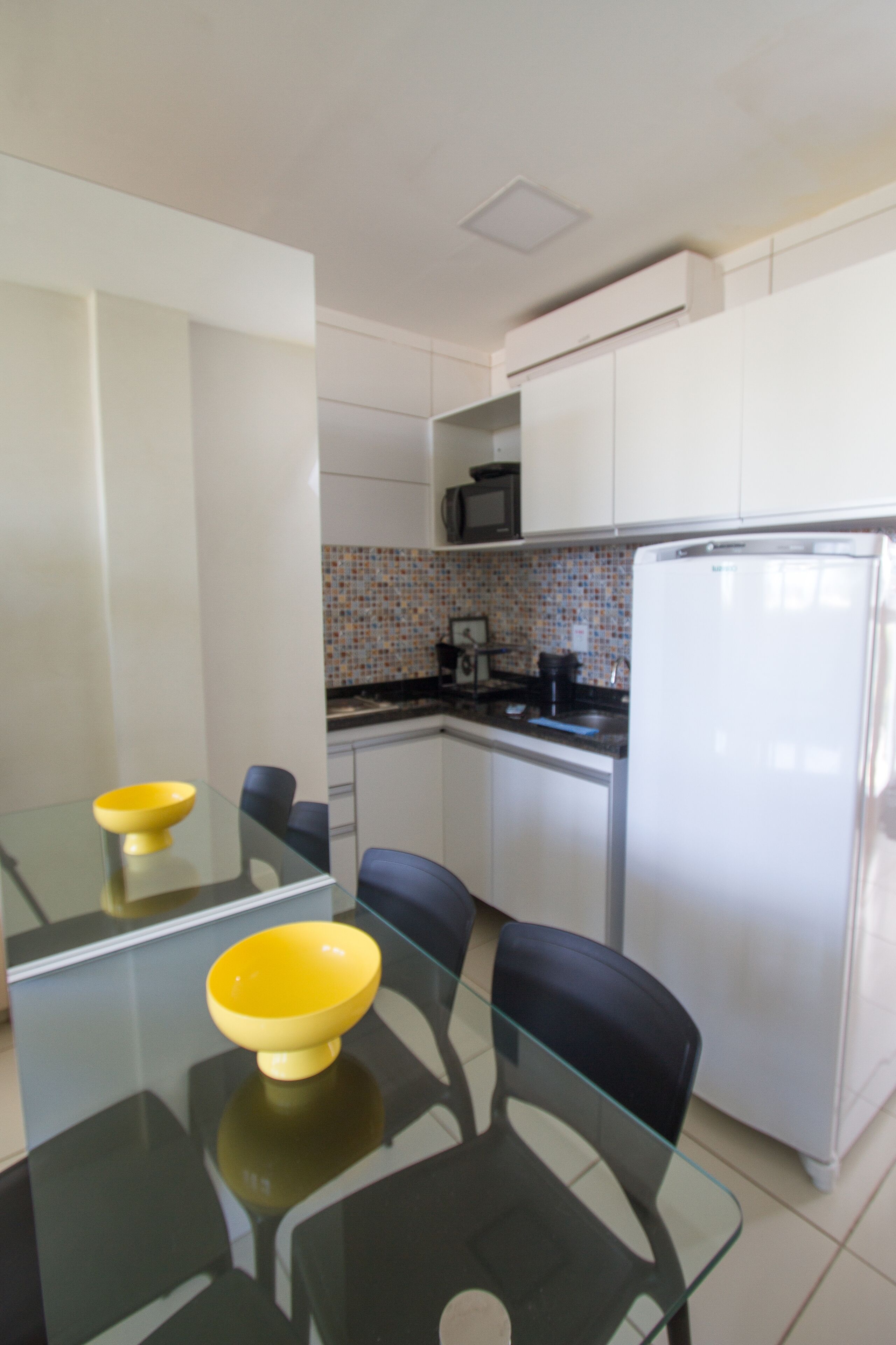 Una cocina moderna con armarios blancos, encimera negra y un microondas.