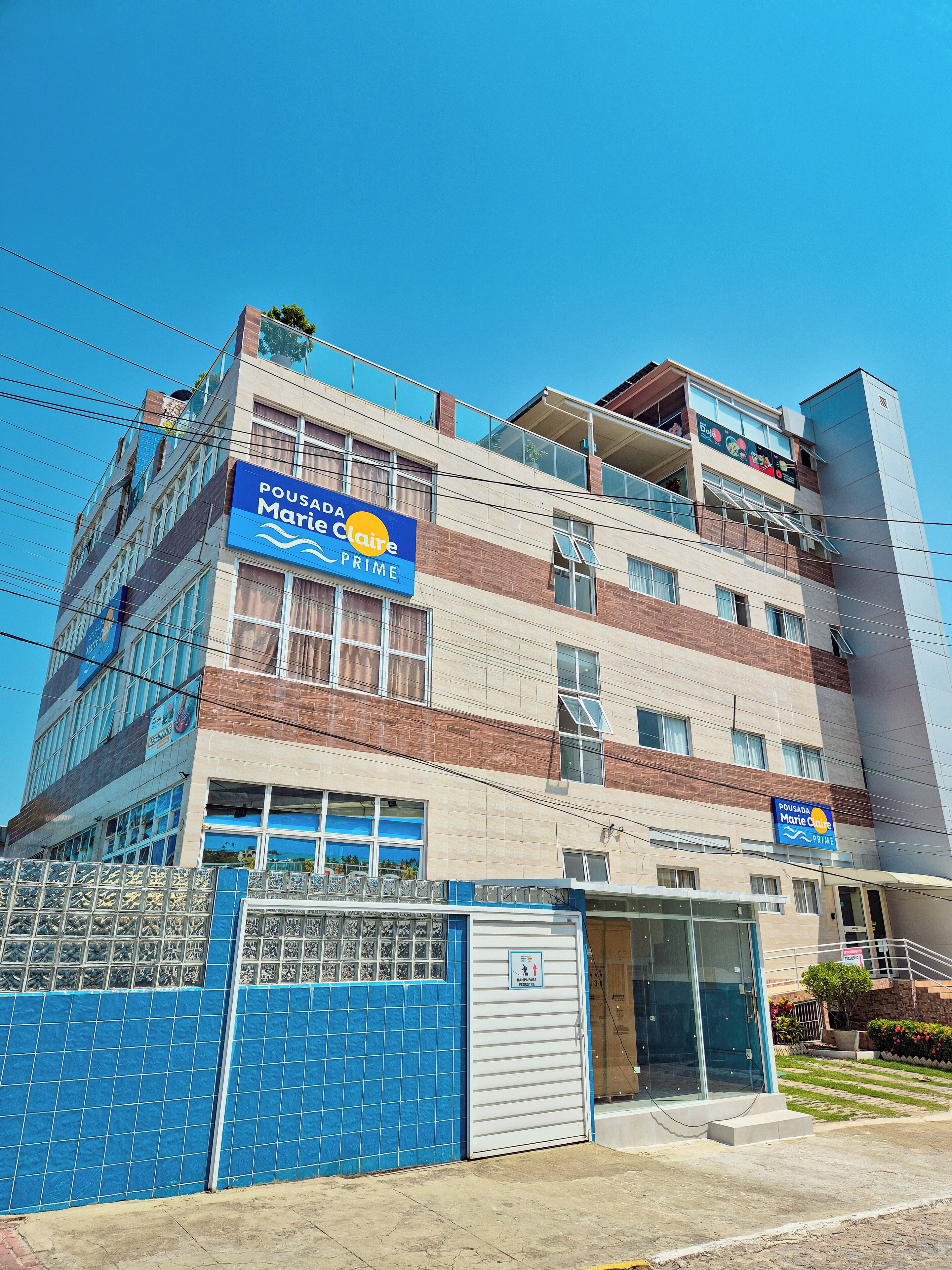 Un edificio de varios pisos con un letrero llamativo que dice "POUSADA Marie Claire PRIME".