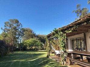 A wooden house with a covered porch, a grassy yard, and a hammock. - Tacheles (José Ignacio)