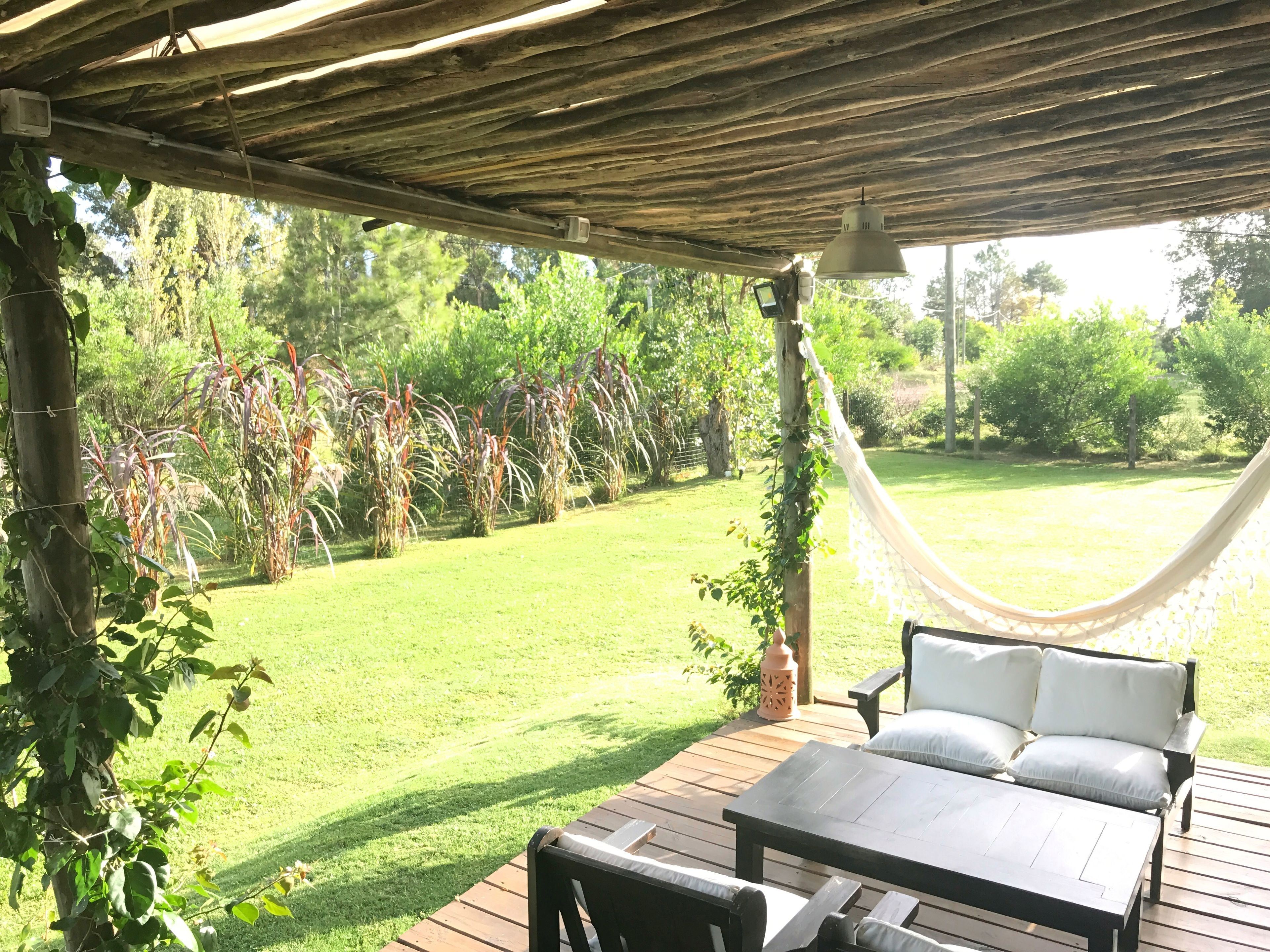 A wooden deck with a hammock, a sofa, and a table.