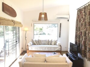 A living room with a sofa, a TV, and a window with a view of the outdoors. - Tacheles (José Ignacio)