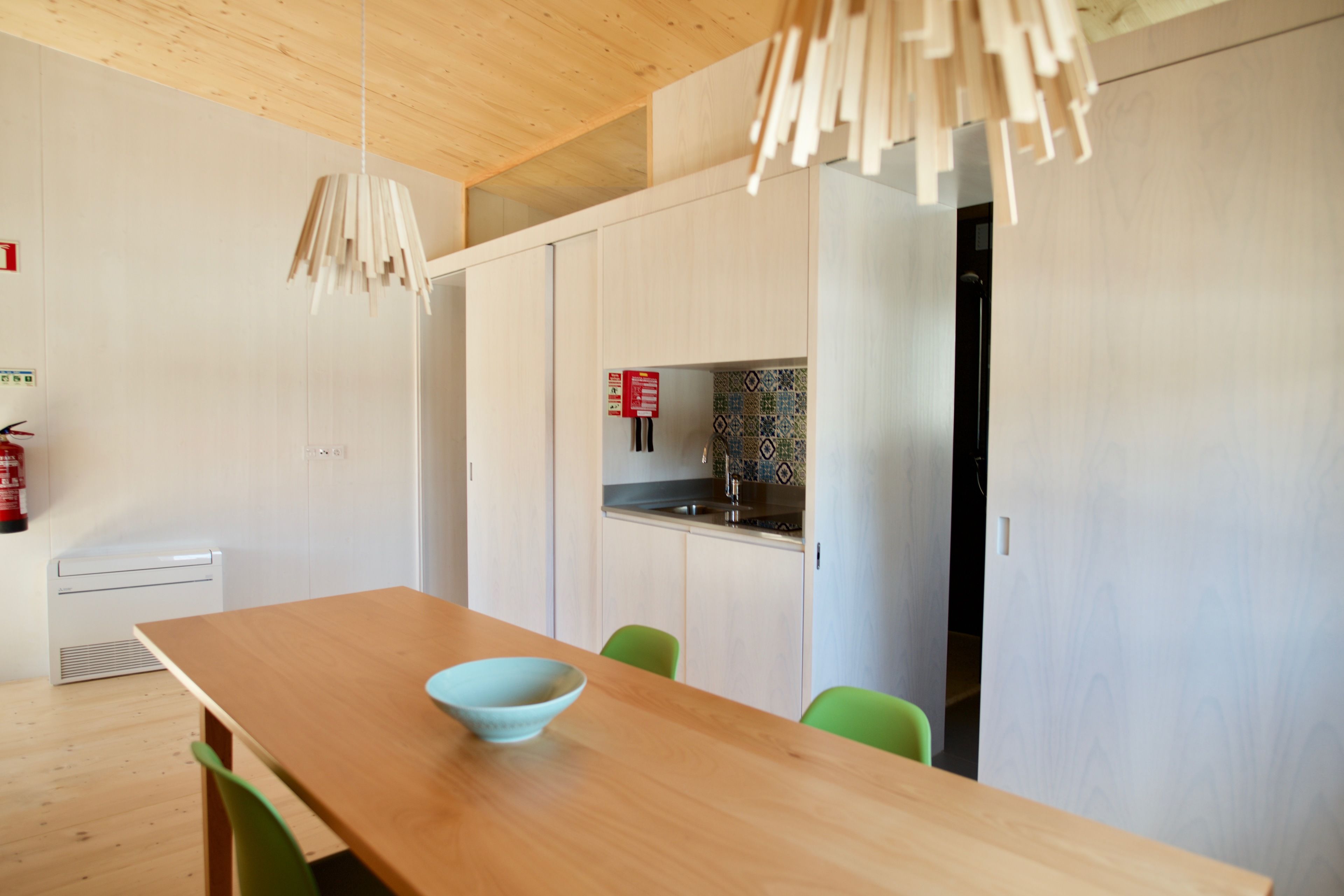 Une cuisine moderne avec des armoires blanches, un plafond en bois et un extincteur bien visible.