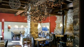 A restaurant interior with hanging spherical light fixtures and a stone wall backdrop. - Hotel El Monegal (Guixers)