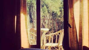 A room with a large window, wicker chairs, and a table. - Hotel El Monegal (Guixers)