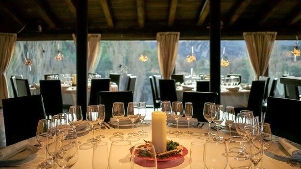 A dining table set for a meal with multiple wine glasses and a central candle, surrounded by chairs. - Hotel El Monegal (Guixers)