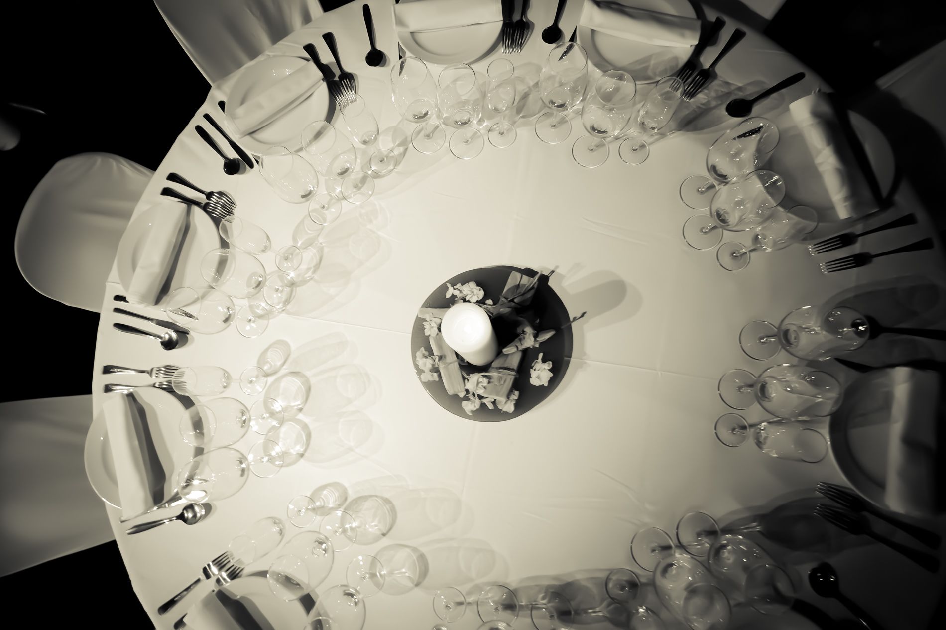 A round dining table with multiple wine glasses and cutlery arranged around it.