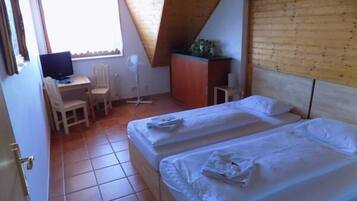 A bedroom with two beds, a desk, a chair, and a small table.