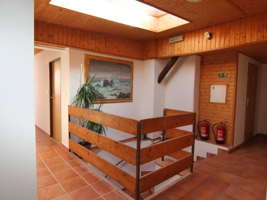Un interior de madera con una escalera, un cuadro y extintores.