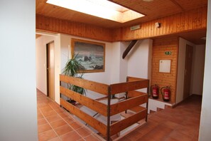 A wooden interior with a staircase, a painting, and fire extinguishers. - Hotel Kréta (Kutna Hora)