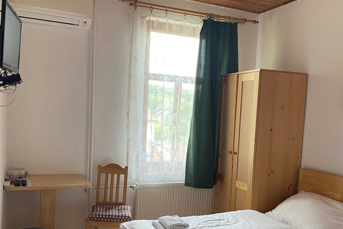 Un dormitorio con dos camas, un armario de madera, un escritorio con silla y una ventana con cortinas.