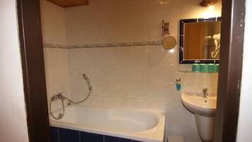 A bathroom with a bathtub, a sink, and a mirror.