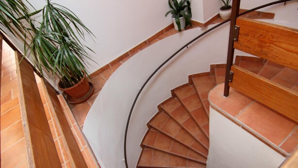 Una escalera de caracol con baldosas de terracota y barandilla de madera.