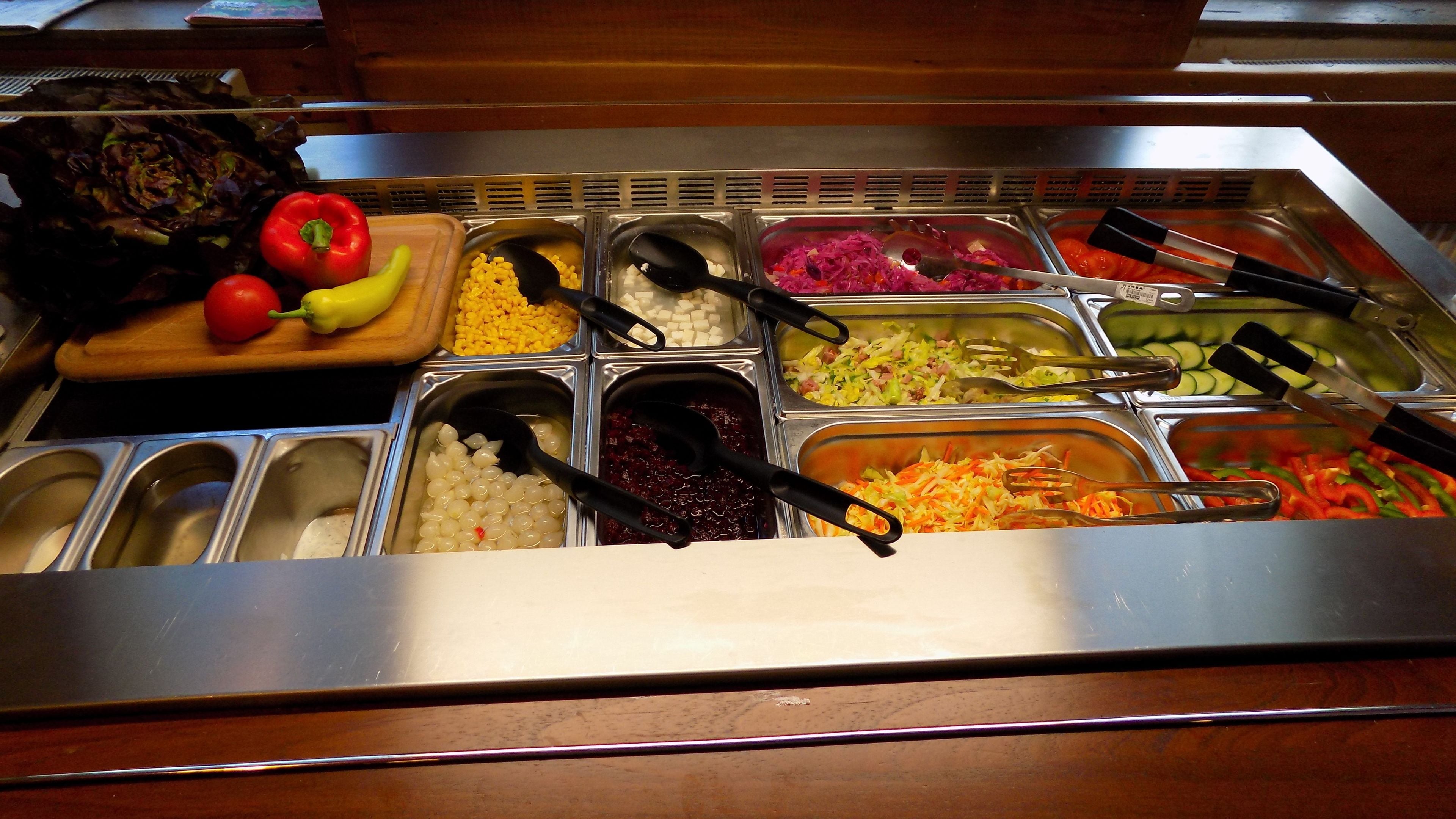 A buffet with various food items including vegetables, fruits, and grains.