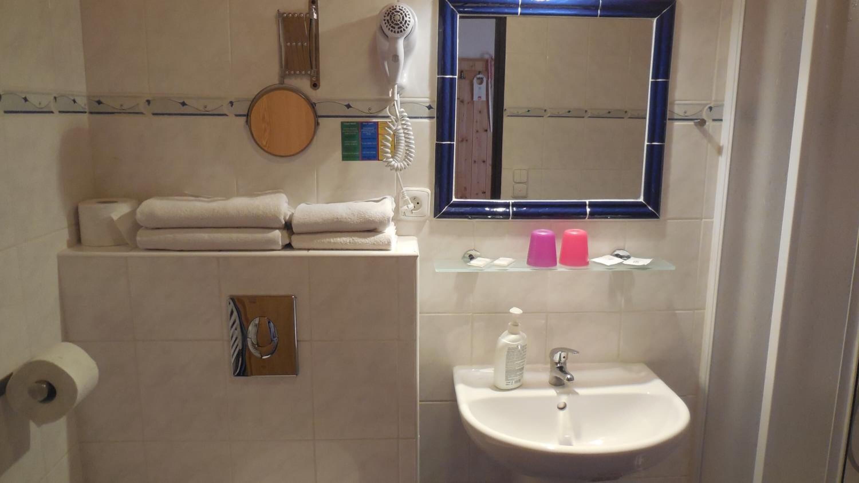 A bathroom with a sink, mirror, towel rack, and a hairdryer.
