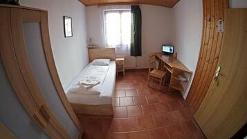 A compact room with a bed, a desk, and a chair.