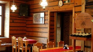 Un interior de madera con una mesa de comedor, sillas, un reloj, un televisor y una estantería para vinos.