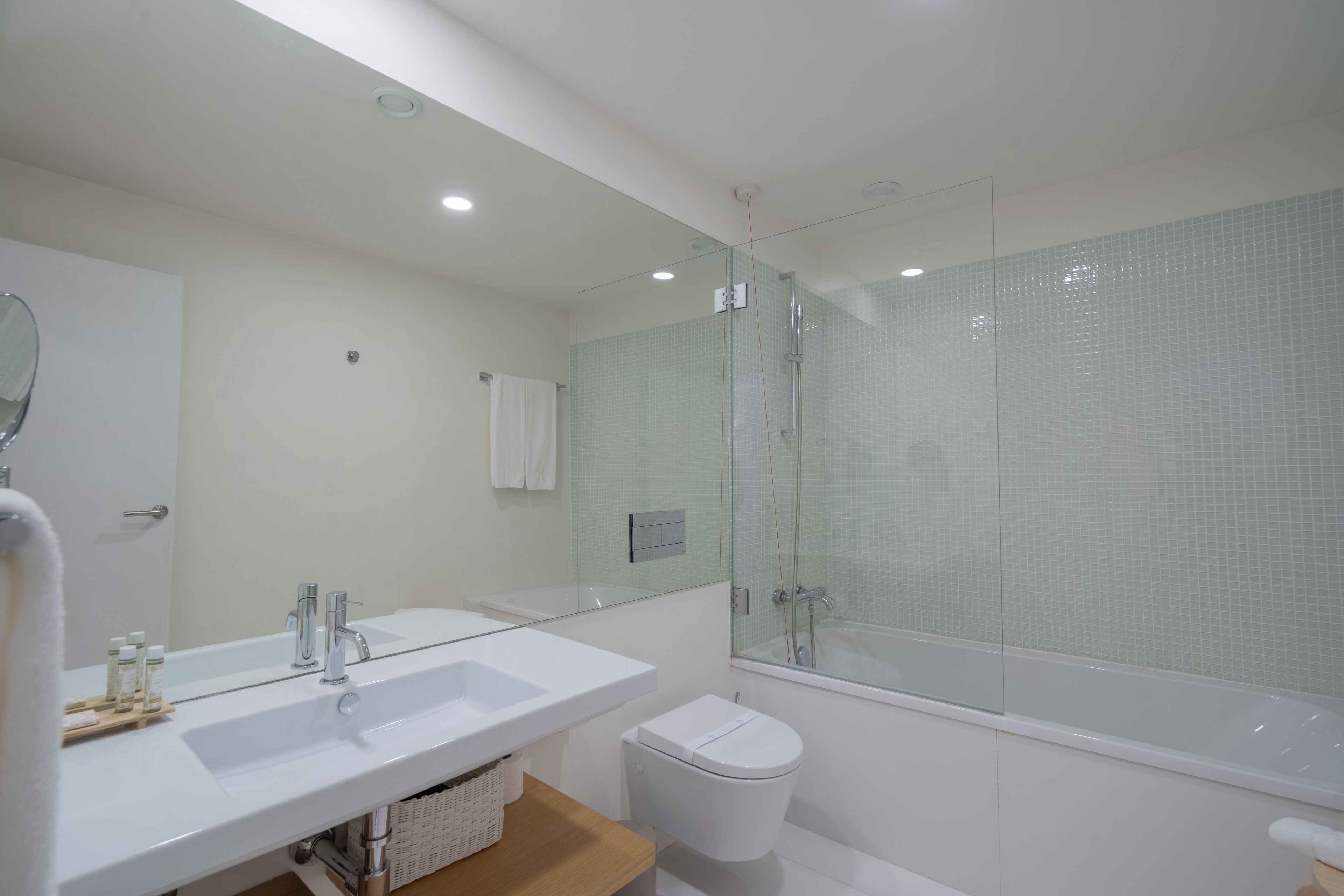 Een moderne badkamer met een grote spiegel, een witte wastafel en een douchecabine met glazen wanden.