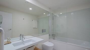 A modern bathroom with a large mirror, white sink, and a glass-enclosed shower area.