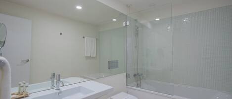Een moderne badkamer met een grote spiegel, een witte wastafel en een douchecabine met glazen wanden.