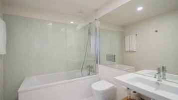Un bagno moderno con doccia vetrata, un water bianco e uno specchio grande sopra un lavabo.