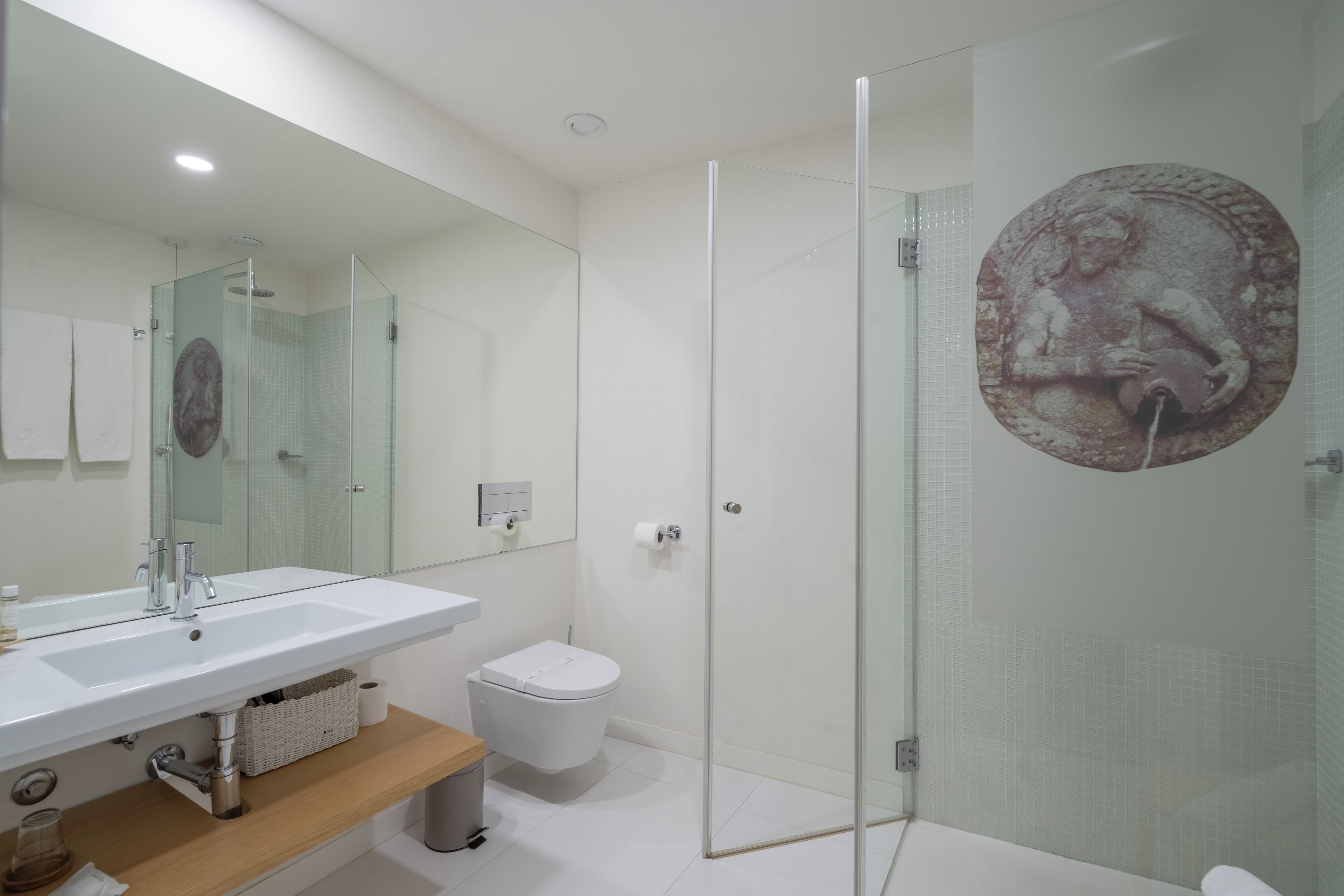 A modern bathroom with a glass-enclosed shower, a white sink, and a toilet.