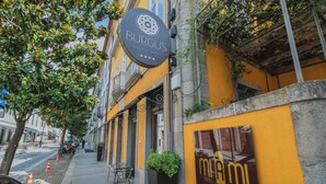 A building with a yellow facade, a sign for 'Burgus Tribute Hotel', and a 'Miami drinks & food' sign. - Burgus Tribute & Design Hotel (Braga)