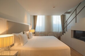 A modern hotel room with a large bed, a TV, a desk, and a staircase. - Burgus Tribute & Design Hotel (Braga)