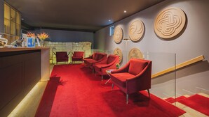 A modern interior with a red carpet, red chairs, a stone wall, and wooden accents. - Burgus Tribute & Design Hotel (Braga)
