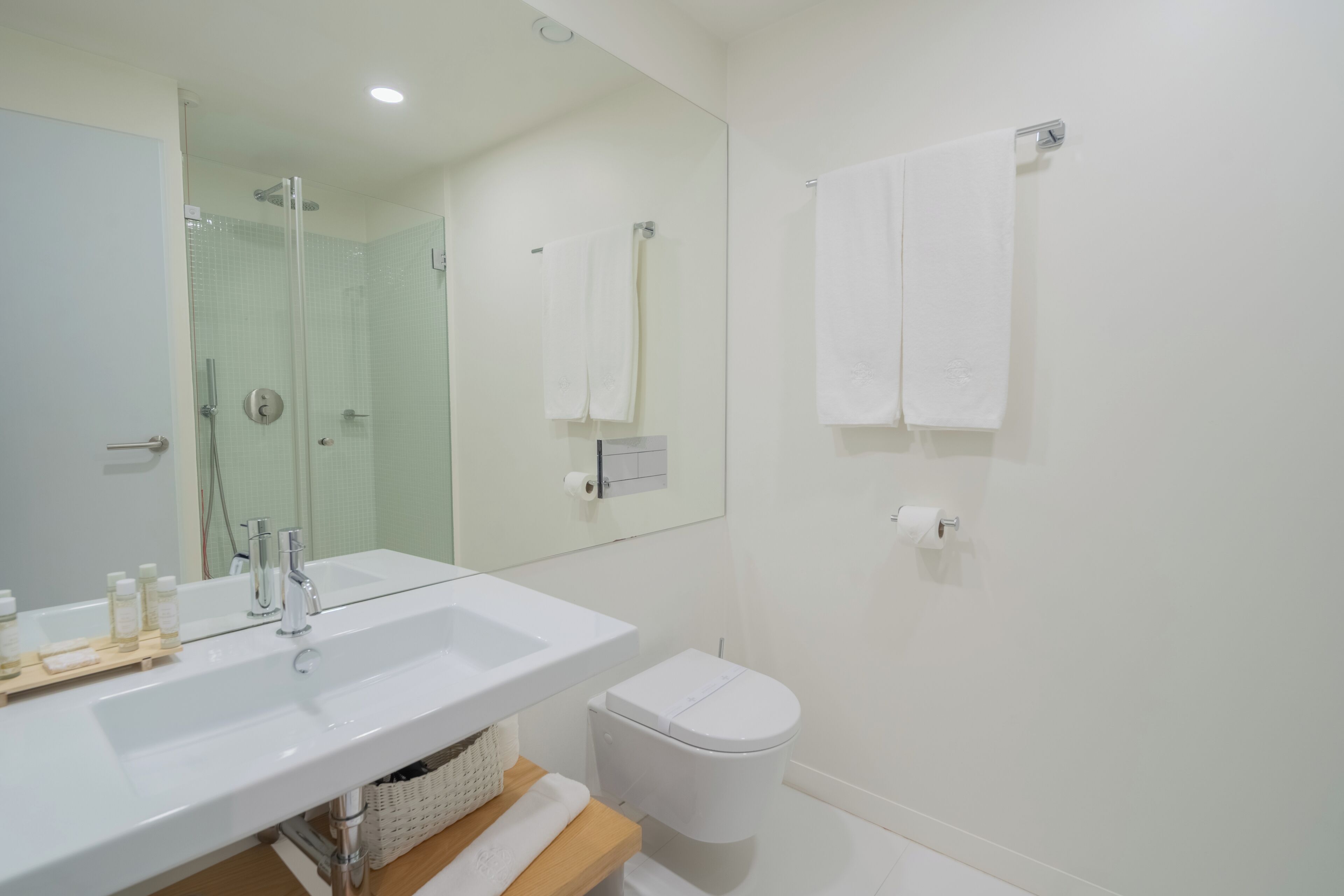 A modern bathroom with a white sink, mirror, and toilet.